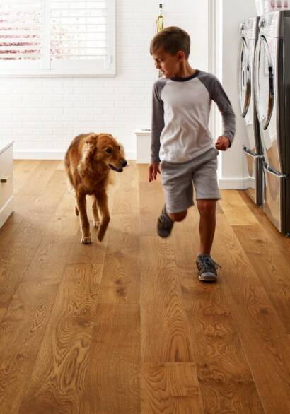 Boy with his Golden Retriever dog walking on their tough wide plan wood laminate laundry room flooring