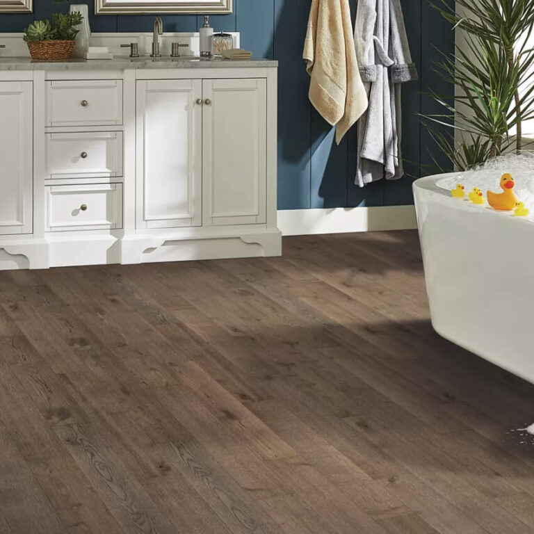 bathroom with warm toned laminate flooring and a free standing white tub