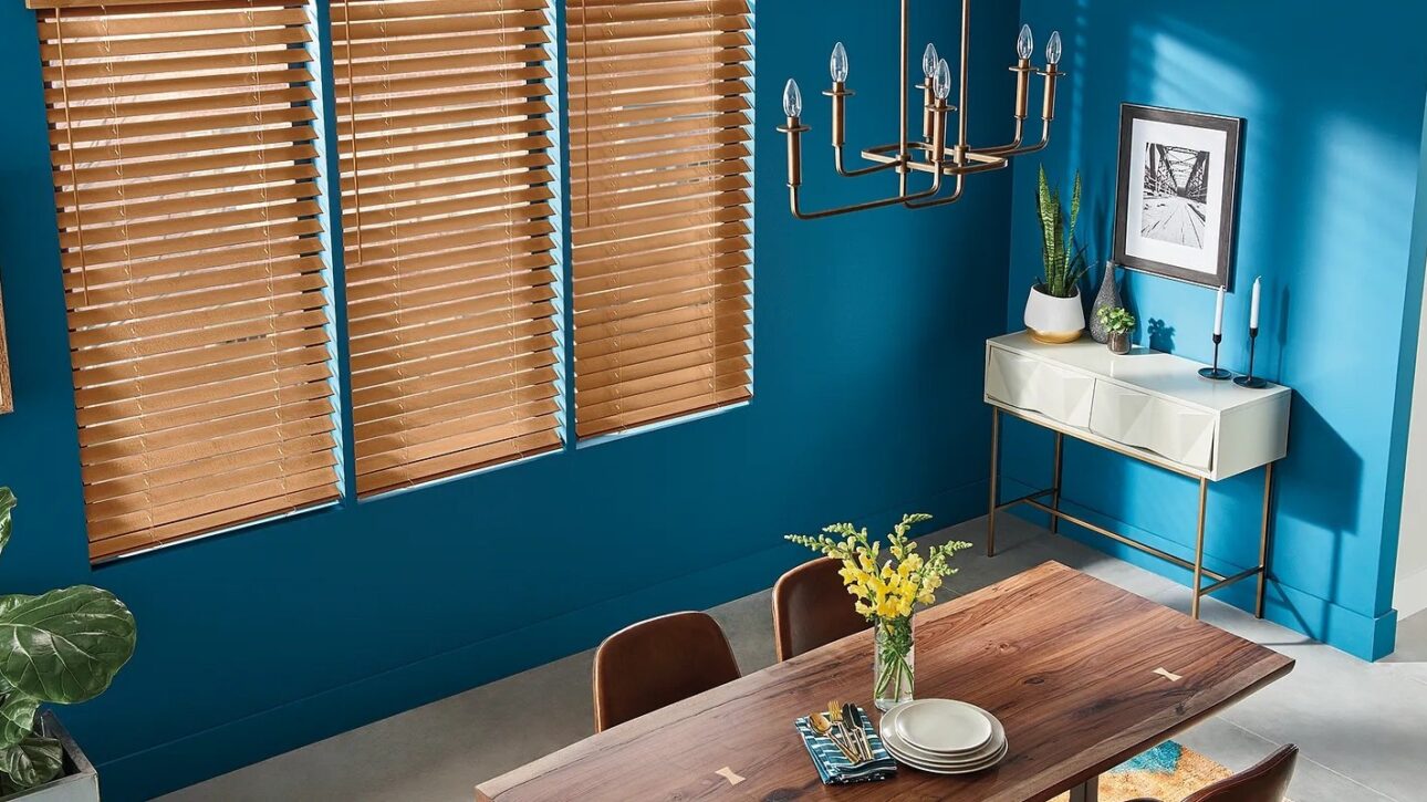 Wood blinds shown in a dining area with deep blue walls