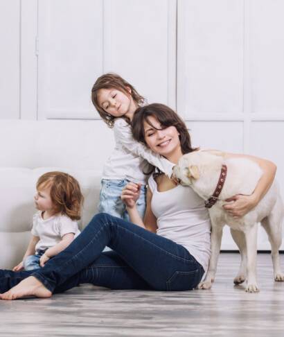 mom playing with her two young children and family dog on their luxury vinyl plank flooring