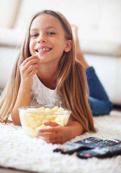 young girl eating popcorn white laying on the carpet